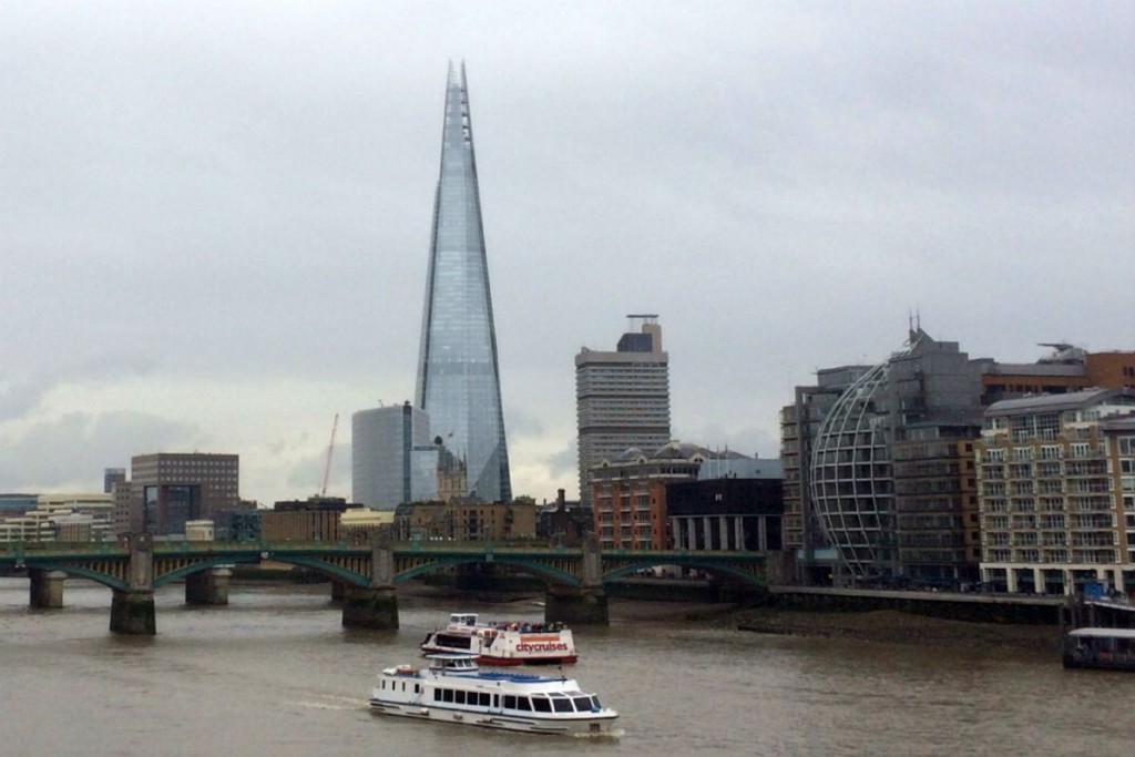 A view from the Millennium Bridge of the Shard. There is a tourist boat on the river.