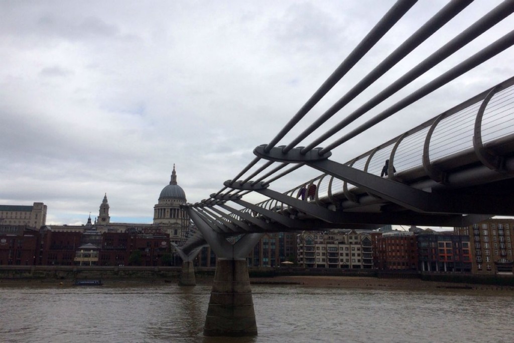 A close up of the underside of the Millennium Bridge with St Paul's in the background.